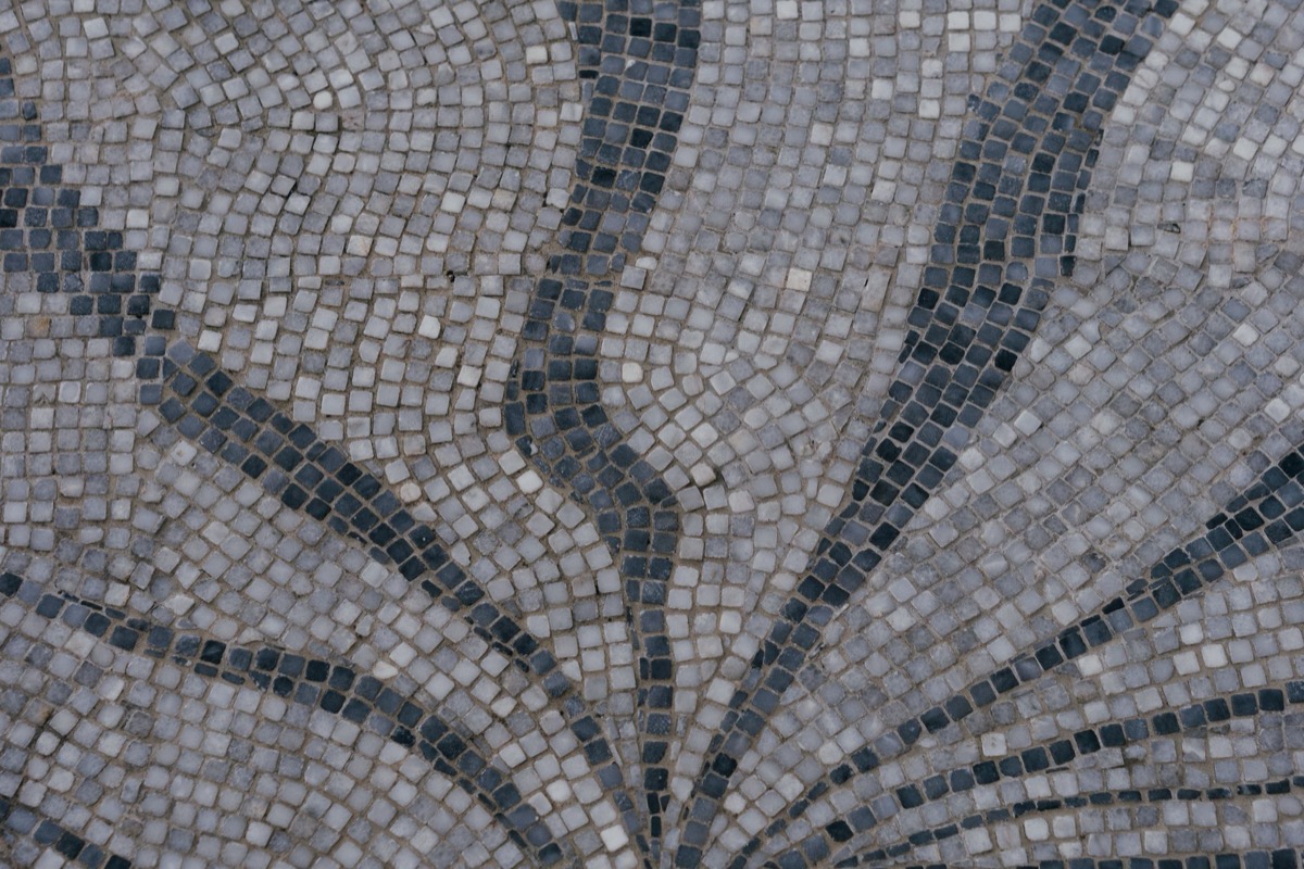 Close-up of a damaged grout line between light-colored floor tiles, showing significant cracking.
