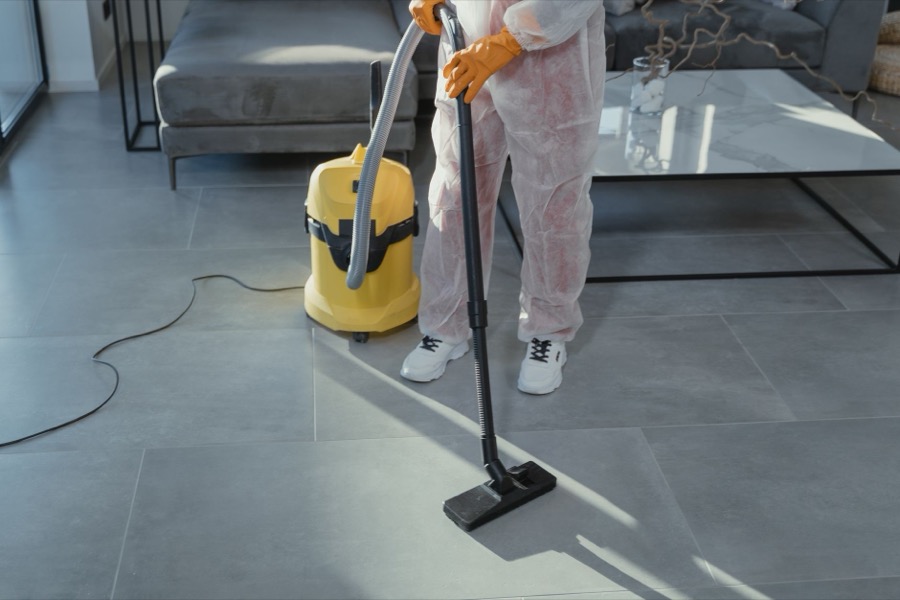 A close-up shot of a hand holding a specialized grout removal tool over a tile joint.