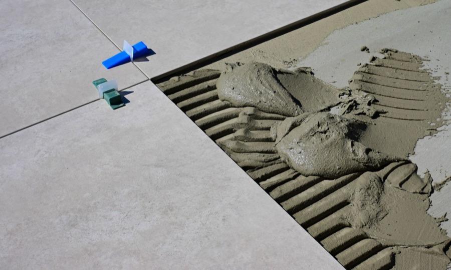 Detail shot of a hand applying fresh grout to tile lines with a rubber float.