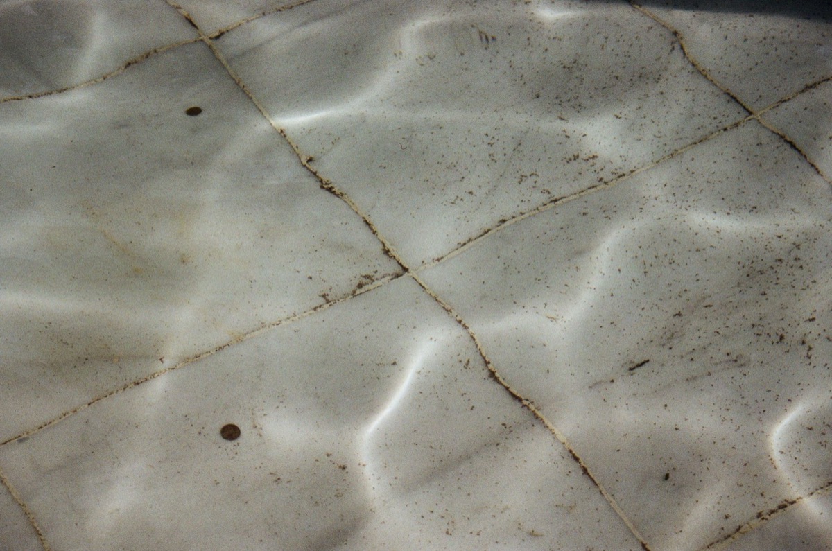 Close-up of a damaged, cracked grout line between ceramic tiles in a bathroom.
